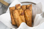 fried eggrolls draining in a spider strainer Shot