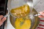 whisking butter into egg yolks to make hollandaise sauce Shot