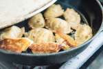 pot stickers frying in a cast iron pan Shot