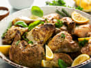 Cooking Class - Elegant Dishes for an Anniversary in Northern Virginia: Golden roasted chicken pieces served in a white dish, garnished with fresh herbs and lemon wedges.