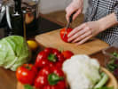 Cooking Class - Mastering Your Knife in Northern Suburbs: Chopping a red bell pepper on a wooden cutting board surrounded by vegetables.