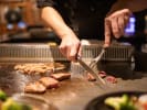 Hibachi Catering - Showstopping Hibachi Grill Fare: chef cooking meat on hibachi stainless grill