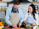Cooking Class - Tuscan Steak Celebration Dinner - Date Night in South Bay & Peninsula: a couple cutting vegetables with aprons on in a kitchen