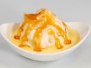 Cooking Class - Downton Style Dining in South Bay & Peninsula: Peach dessert – A scoop of vanilla ice cream topped with warm peach slices and caramel sauce, served in a white bowl.