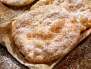 Cooking Class - Classic Bakery Favorites - Family Fun in Northern Suburbs: Crisp golden elephant ears dusted with powdered sugar, resting on parchment paper.
