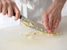 Cooking Class - Dinner Alla Milanese in Downtown Dallas: Chopping fresh garlic on a white cutting board.