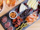 Cooking Class - Elegant Coastal Surf & Turf - Date Night: A charcuterie board with a variety of meats, cheeses, pickles, nuts, and bread, arranged beautifully on a slate platter