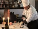 Private Chef - Satisfying French Favorites: A chef is pouring wine into a glass for a guest seated at a candle lit dining table during the private chef class