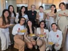 Private Chef - Traditional Indian Cuisine Tastes: A group of twelve women poses smiling in a home kitchen, each holding a plate of food.