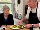 Cooking Class - Mediterranean Recipes Made Simple in San Diego: A man wearing a white shirt and black apron is plating a dish with romaine lettuce and chickpeas in a bright, modern kitchen