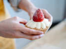 Cooking Class - Cupcake Celebration - Family Fun in Northern Suburbs: A person holding a cupcake topped with whipped cream and a fresh strawberry
