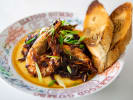Cooking Class - Fat Tuesday on Thursday in DC: A plate of creamy shrimp grits topped with blackened chicken, scallions, and a rich, spicy sauce