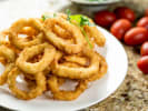 Cooking Class - Little Bites With Big Flavors in Northern Suburbs: A white plate filled with crispy golden fried calamari rings, served with lemon wedges and cherry tomatoes