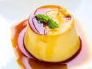 Cooking Class - Spanish Paella Three Ways: Caramel flan garnished with mint on a plate of caramel sauce