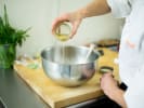 Team Building Cooking Class - Mystery Menu Challenge in Chicago: Chef adding an ingredient to a mixing bowl during a cooking class
