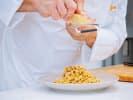 Online Pasta Making Class - Homemade Bolognese Pasta: chef shredding parmesan on pasta bolognese