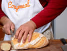 Cooking Class - Bread and Homemade Spreads in San Fernando Valley: Chef in an apron slicing a crusty loaf of homemade bread on a wooden board