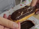 Cooking Class - Chocolate-Dipped French Éclairs in Culver City: Close up of a freshly baked éclair being dipped into rich chocolate glaze
