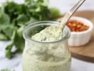 Cooking Class - Lomo Saltado & Peruvian Classics: Close up of a jar of creamy green aji verde sauce with a spoon resting inside