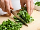 Cooking Class - Lomo Saltado & Peruvian Classics: Close up of hands finely chopping fresh cilantro on a wooden cutting board