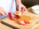 Cooking Class - Savory & Sweet Mediterranean Mezze: Close up of hands slicing red bell pepper and tomato on a wooden cutting board for muhammara