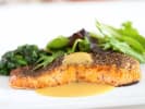 Cooking Class - Tour de France Celebration in Miami: Dijon-crusted salmon with greens – A plated fillet of salmon topped with Dijon crust, served with wilted greens and a light sauce.