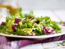 Cooking Class - Bistro Elegance: A French Culinary Evening in Downtown Dallas: Fresh mixed greens salad – A colorful salad with leafy greens, radicchio, and possibly beets or apples, on a white plate atop a purple napkin.