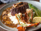 Cooking Class - Elegant Coastal Surf & Turf - Date Night: Filet mignon and lobster tail served on a plate with mashed potatoes, asparagus, and a rich sauce, garnished with lemon