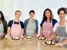 Team Building Cooking Class - French Pastry Bake-Off for Teams: Five participants wearing aprons proudly displaying their decorated desserts during a group pastry making class