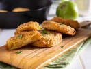 Cooking Class - A Taste of Southern Comfort: Fried green tomatoes served on a wooden board, garnished with fresh herbs and accompanied by a cast iron skillet in the background