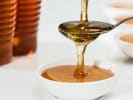Cooking Class - A Taste of Southern Comfort: Honey being drizzled from a spoon into a small white bowl, with jars of honey in the background