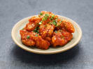 Cooking Class - Seoul Kitchen in Manhattan: Korean fried chicken with scallions and sesame â€“ A plate of crispy glazed Korean chicken garnished with sliced scallions and sesame seeds.