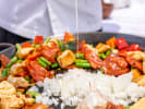 Cooking Class - Spanish Paella From Scratch: Overhead view of a paella pan with chicken thighs, chorizo, tomatoes, and rice cooking together
