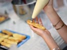 Team Building Cooking Class - French Pastry Bake-Off for Teams: Participant piping cream filling into a freshly baked éclair during a hands on pastry making class