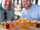 Food Tour - Craft Breweries of New Orleans in New Orleans: Two friends smiling behind flights of craft beer at a New Orleans brewery tour stop