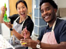 Cooking Class - Master French Macarons Step by Step in Culver City: Two smiling participants decorating colorful macarons during a hands on baking class