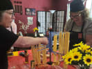 Cooking Class - Pasta on Your Plate in Las Vegas: Two women wearing black chef hats and aprons are carefully hanging fresh pasta on a drying rack at a red covered table.