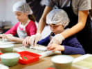 Kids' Cooking Class - Sushi Art for Young Chefs: a cooking class teacher is helping kids to roll sushi