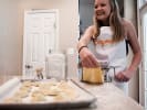 Kids' Cooking Class - Little Chefs Make Pasta: a young girl is laughing while wearing Cozymeal apron and rolling pasta dough