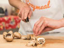 Cooking Class - Vegan Italian Favorites in Boulder: ands slicing fresh mushrooms with a knife on a wooden cutting board