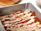Cooking Class - The Five Mother Sauces: bechamel sauce being poured over lasagna bolognese