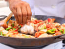 Cooking Class - Paella and Mediterranean Cuisine: chef making paella with fresh garlic, peppers, meat and seafood