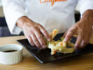 Cooking Class - Craft an Elevated Four-Course Sushi Experience in Toronto: chef plating vegetable tempura with Cozymeal apron
