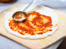 Cooking Class - Gluten-Free Pizza Techniques: chef putting marinara on pizza dough