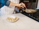 Cooking Class - Traditional Flavors of France in Northern Suburbs: Chef cooking scallops on stovetop – A person searing scallops in a pan on the stove, with a plate of raw scallops on the marble counter nearby, mid-prep during the Bastille Day Feast cooking class.