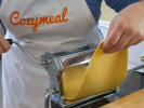 Cooking Class - Fresh Pappardelle and Bolognese Sauce in Charlotte: person with Cozymeal apron rolling fresh pasta sheet