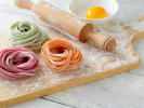 Cooking Class - Make Rainbow Pasta in Baltimore: fresh rainbow colored fettuccine pasta resting on a wooden board and dusted with flour