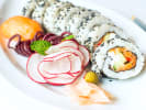 Cooking Class - Make Sushi Like a Pro in Houston: vibrant salmon and cucumber sushi on a white plate next to assorted veggies