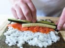 Cooking Class - Make Sushi Like a Pro in Houston: close up of a person rolling salmon and cucumber filled sushi