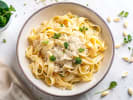 Cooking Class - Master Fresh Pasta & Alfredo Sauce in Toronto: Top view of tabletop with a bowl of Fettucine pasta with creamy Alfredo sauce, herbs and plenty of Parmesan cheese